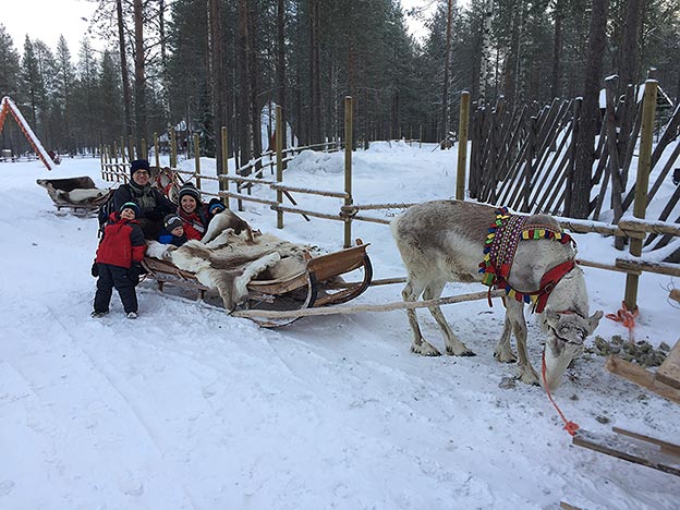 The Newcamp family in snowy Finland, riding in a sleigh pulled by reindeer