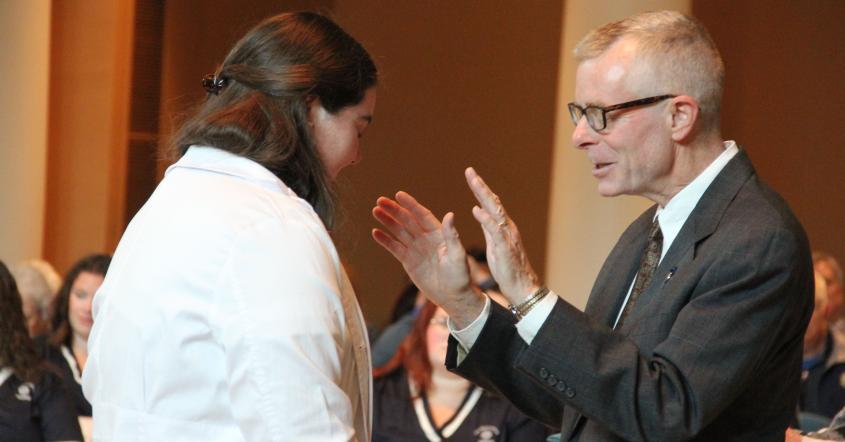 Faculty Rick Baker prays over nursing student