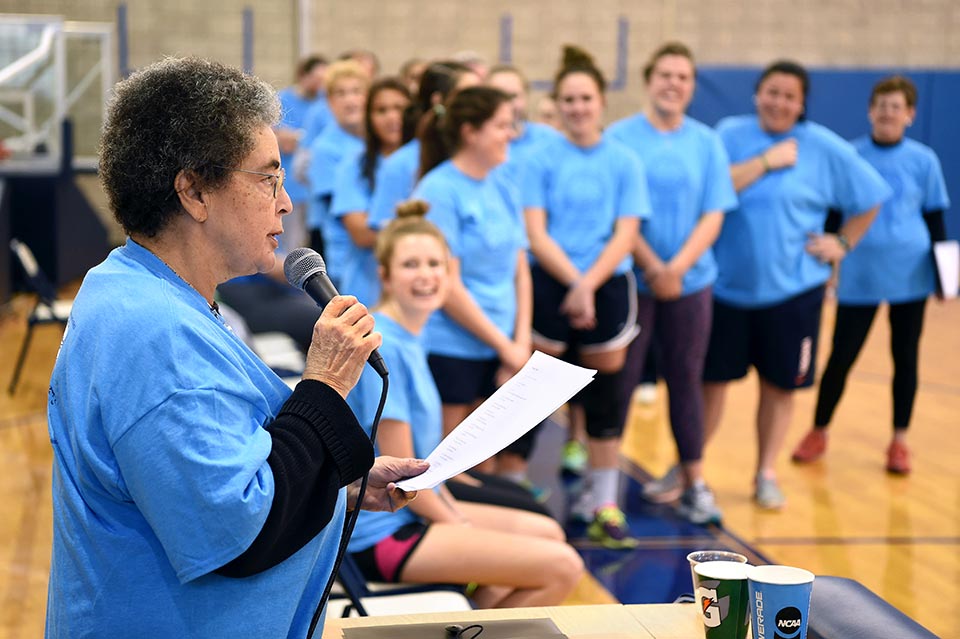 Sister Eva Mary Hooker holds a microphone while reading her poem courtside