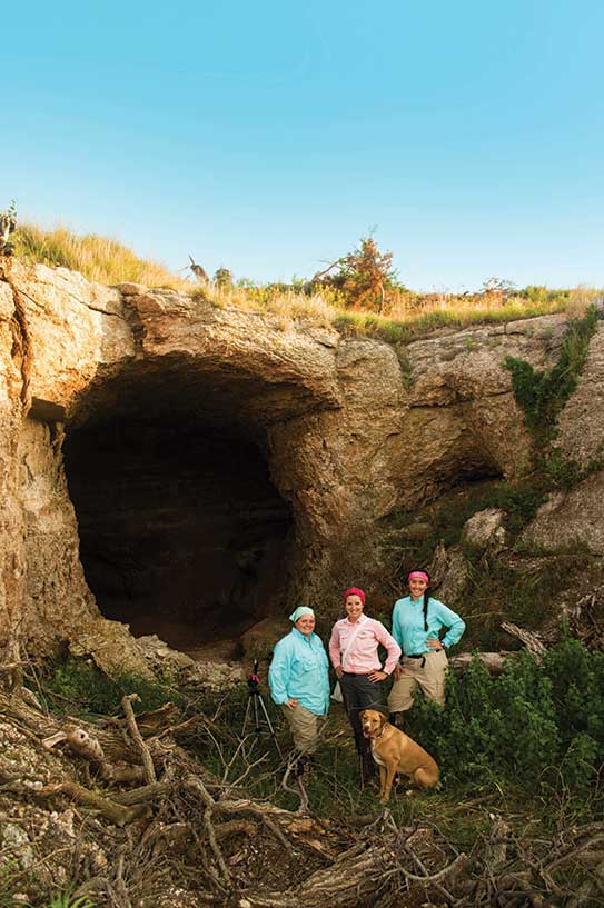 Cassi Mardis ’17, professor Laura Kloepper, her dog, Kaipo, and Stephanie Dresseen ’17 outside of a cave in Atena, KS.