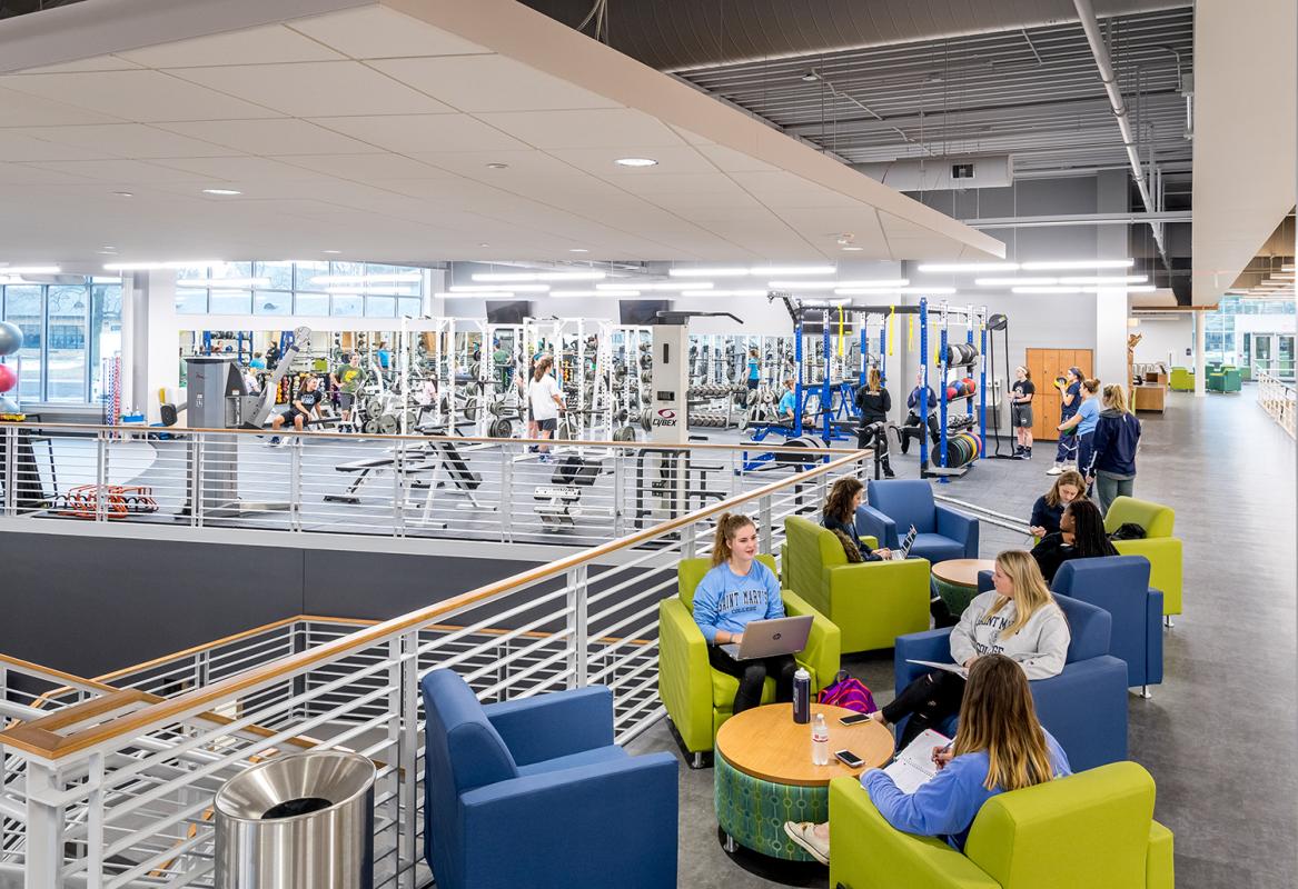 View of main level with a lounge in the foreground and weight training area in the background.