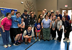 Group of children, young adults, and adults huddled for photo