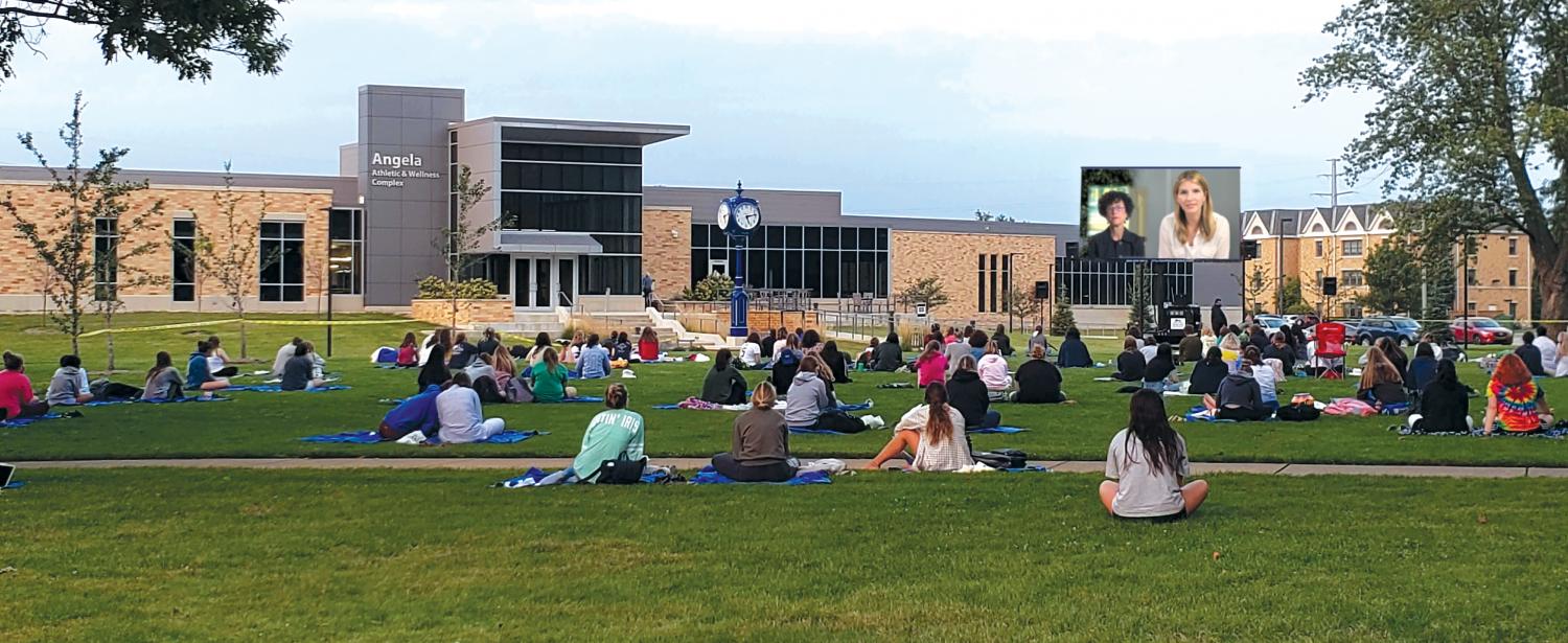 View of students gathered on green watching video interview