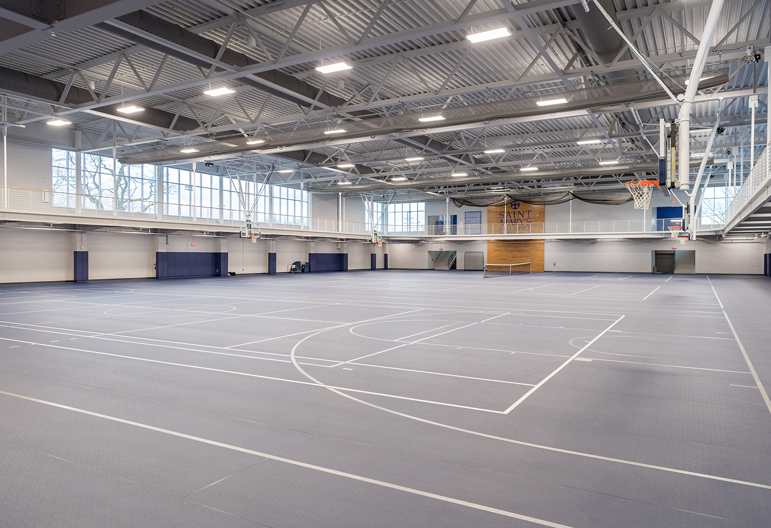 View of expansive new fieldhouse seen from floor with raised running track in view.
