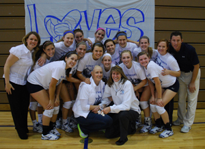 The volleyball team and athletic director Julie Schroeder-Biek pose with Anne Blair Payne '02 before the match.