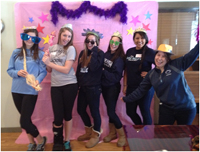 Lacrosse players pose as fairy godmothers in front of photo wall