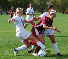 Kari McClowry and Abby Garcia battle with a Calvin player for possession of the ball.