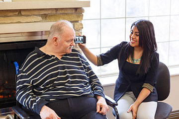 Stephanie Aguilera '16 holds an iPhone up to the ear of the 63-year-old Healthwin patient she is working with on the Music and Memory Project. She loaded some of his favorite music into a music library for him, with the help of his family members. 