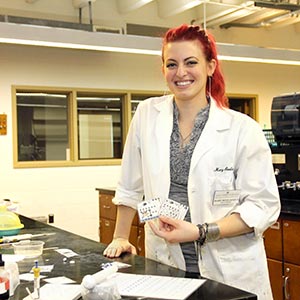 Mary Bevilacqua ’13 holds paper analytical devices, or PADS, that she helped develop with chemistry professor Toni Barstis and other biology students.