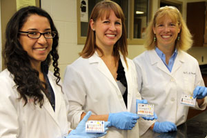 Saint Mary's College chemistry professor Toni Barstis, far right, and from left, Saint Mary's College student researcher Diana Vega Pantoja and SMC alumna researcher Elizabeth Bajema hold the paper analytical device they helped develop at Saint Mary's in 