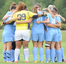 The soccer team huddles before the start of the game.