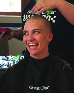 student smiling while getting head shaved