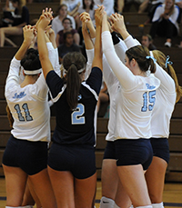 athletes in huddle with hands up