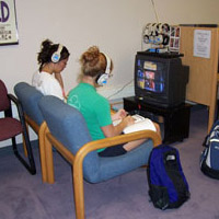 students sitting in front of a monitor in the video lab with headphones on