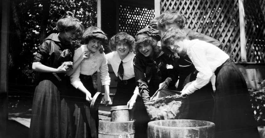 1915 smiling group of students gathering by old barrels