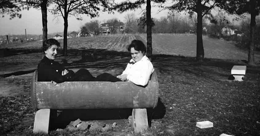 1915 Two students sitting in trough out in a field