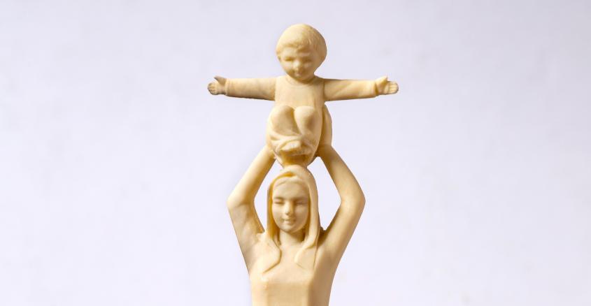 Statue of figure holding child above head