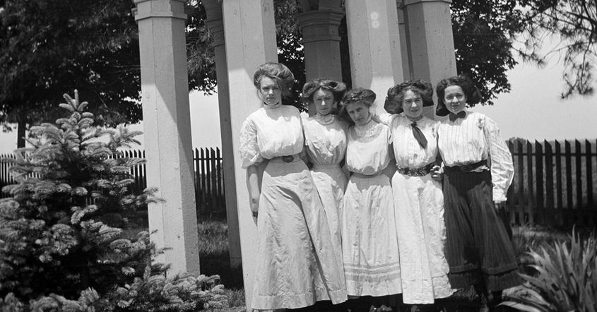 Girls in white dresses standing in group by gazebo