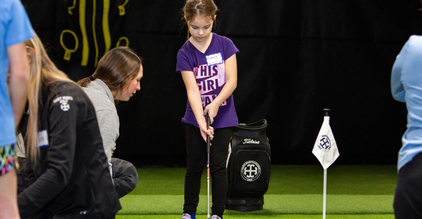 Student athlete works with young camper