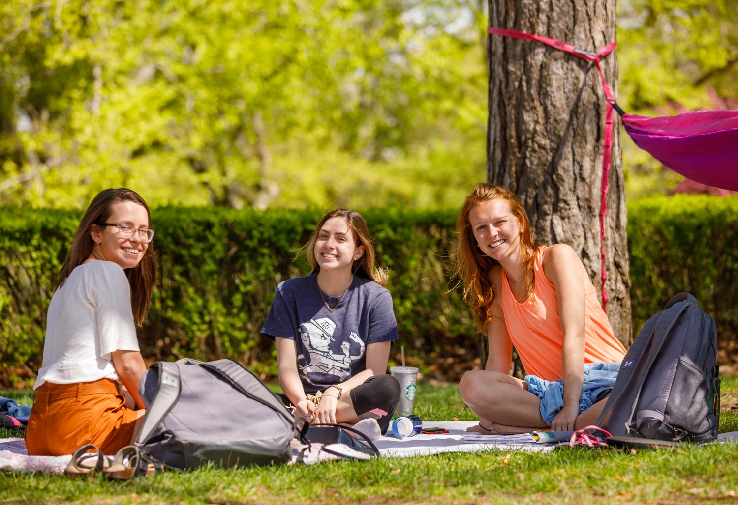 Three students sitting by hammock